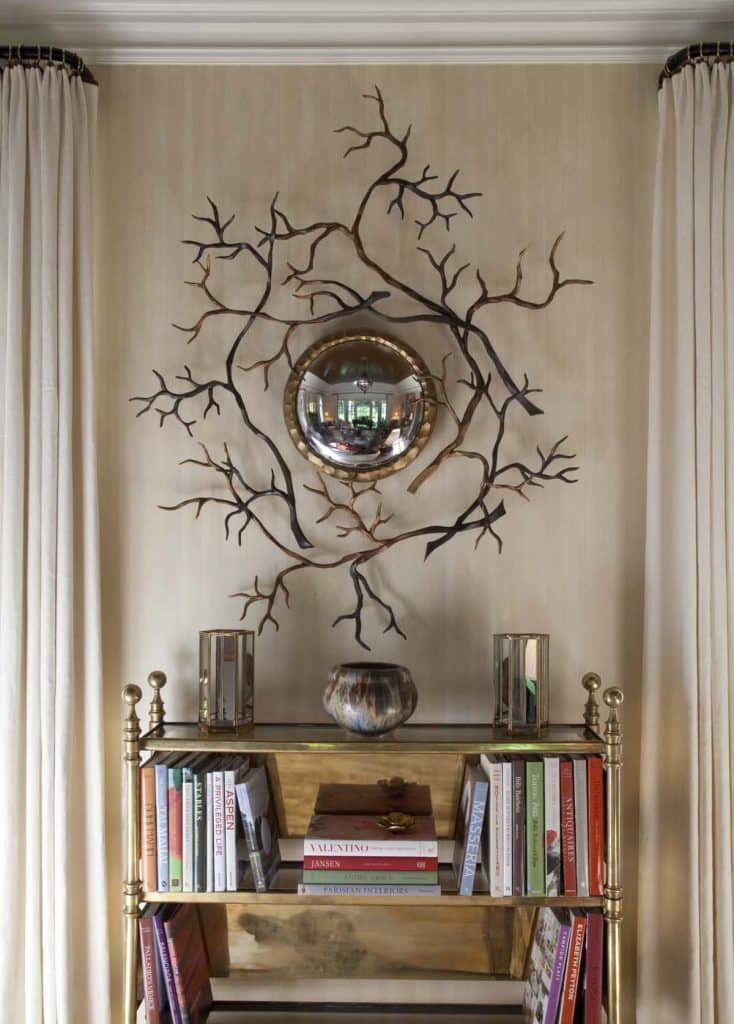 An Hervé van der Straeten Branches mirror hangs above a bookcase in this space by Brian J. McCarthy