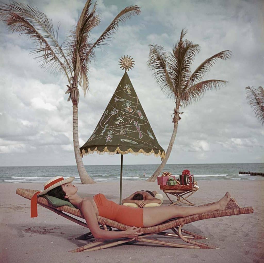 A woman relaxes on a rattan chaise in Palm Beach, as seen on the cover of Holiday magazine in December 1955 and now in the book Rattan: A World of Elegance and Charm, by Lulu Lytle, published by Rizzoli 