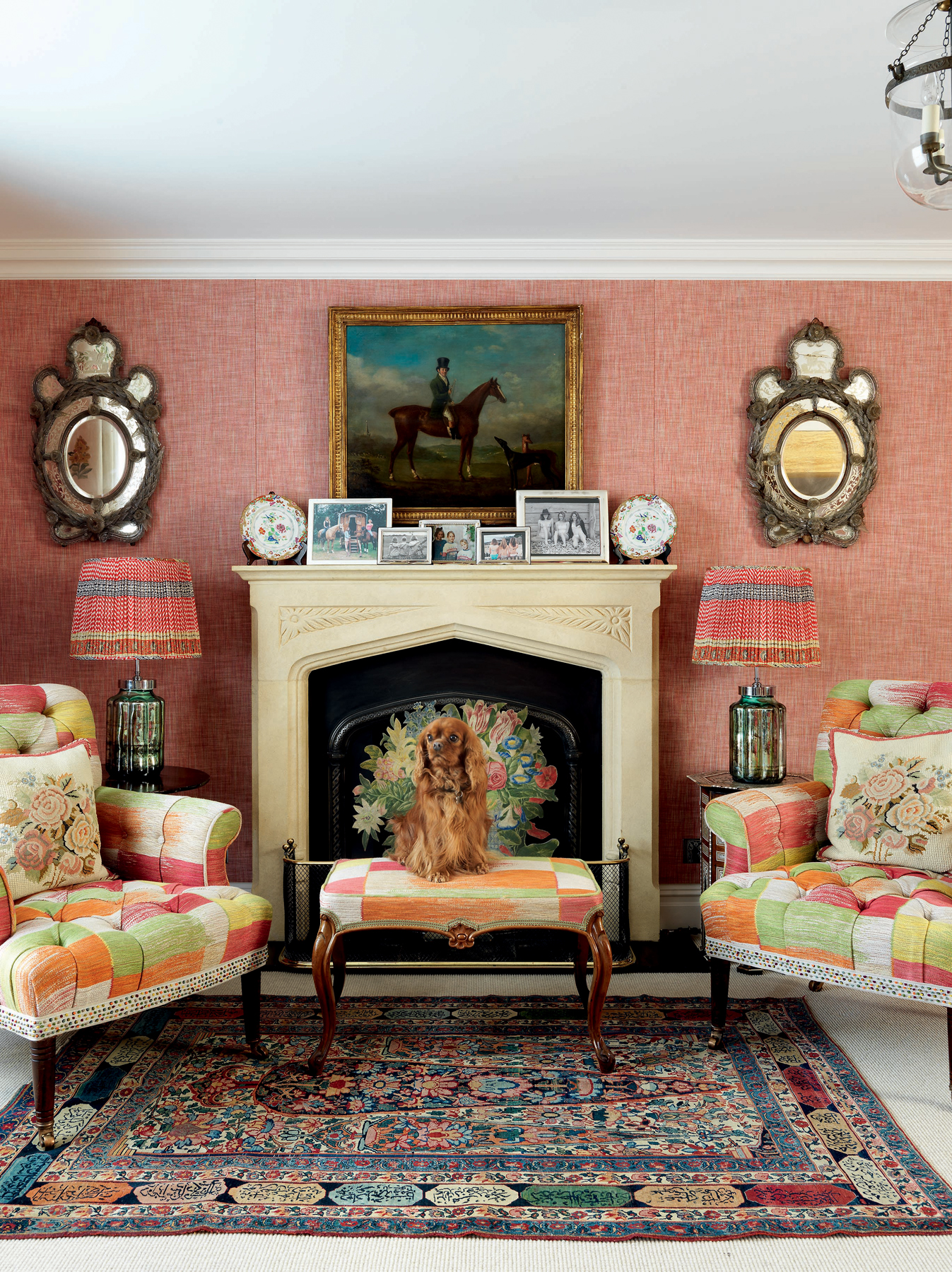 Living room space with matching multicolored armchairs and a dog sitting in front of a fireplace with a decorated mantle