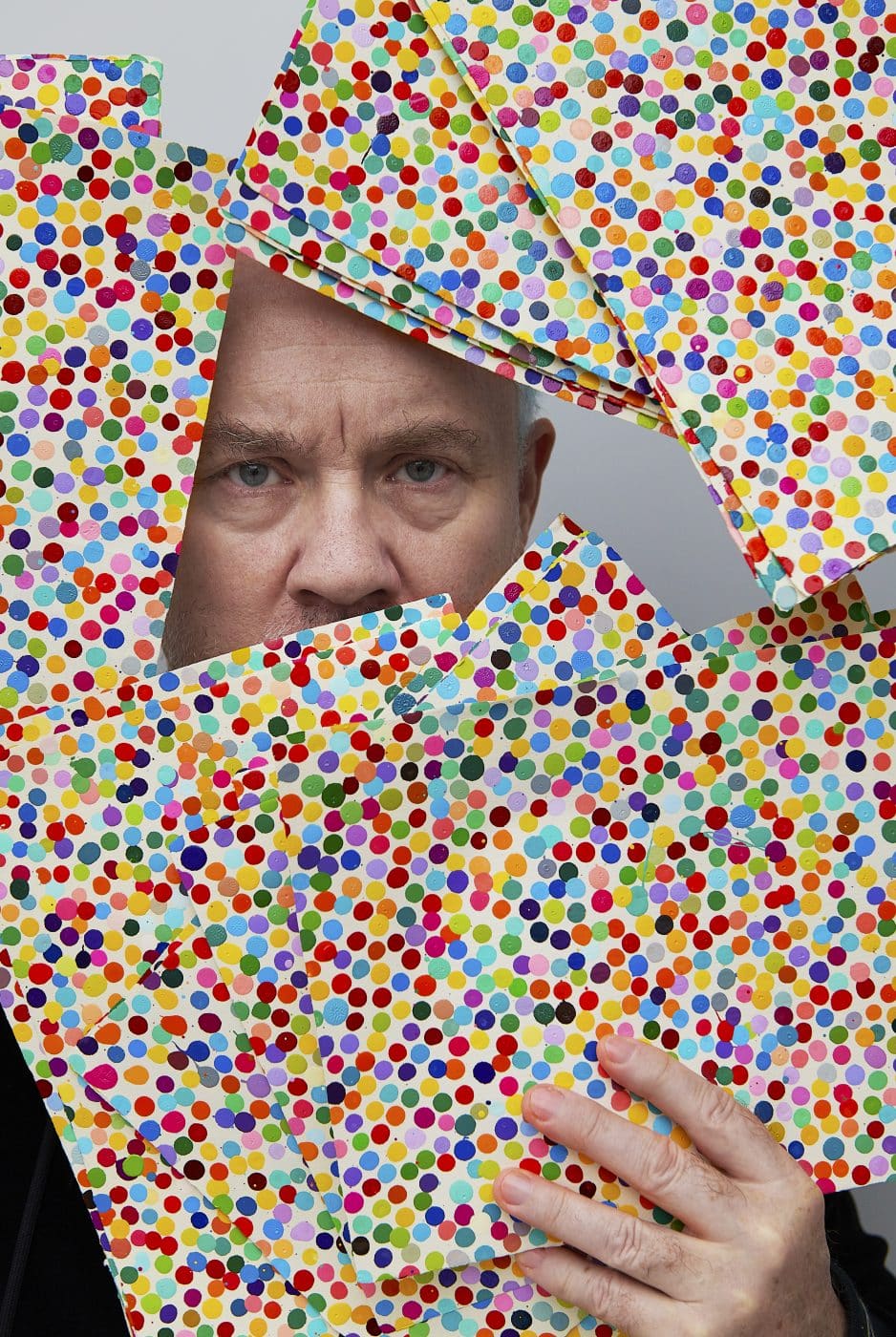 Damien Hirst holding some of his famous dot paintings