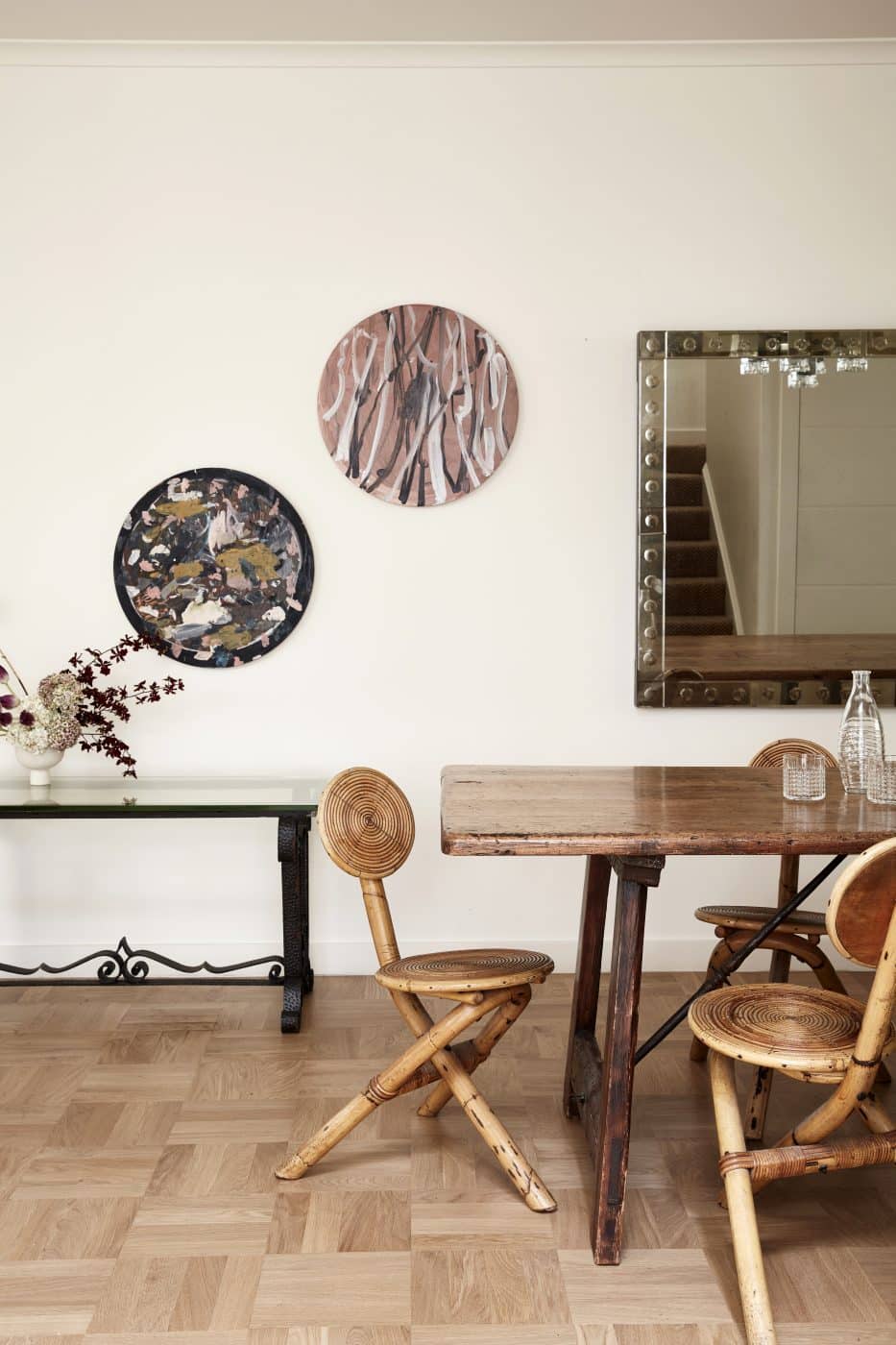 A set of mid-century French cane dining chairs sit at a 19th-century Spanish walnut table under a Venetian glass mirror