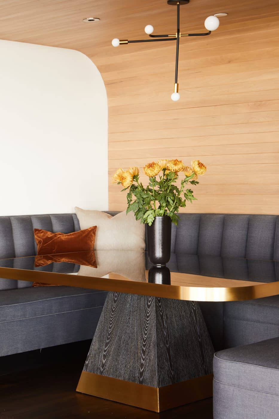The dining nook features a custom banquette plus a table with a cerused-wood and brass base and a smoked-mirror top.