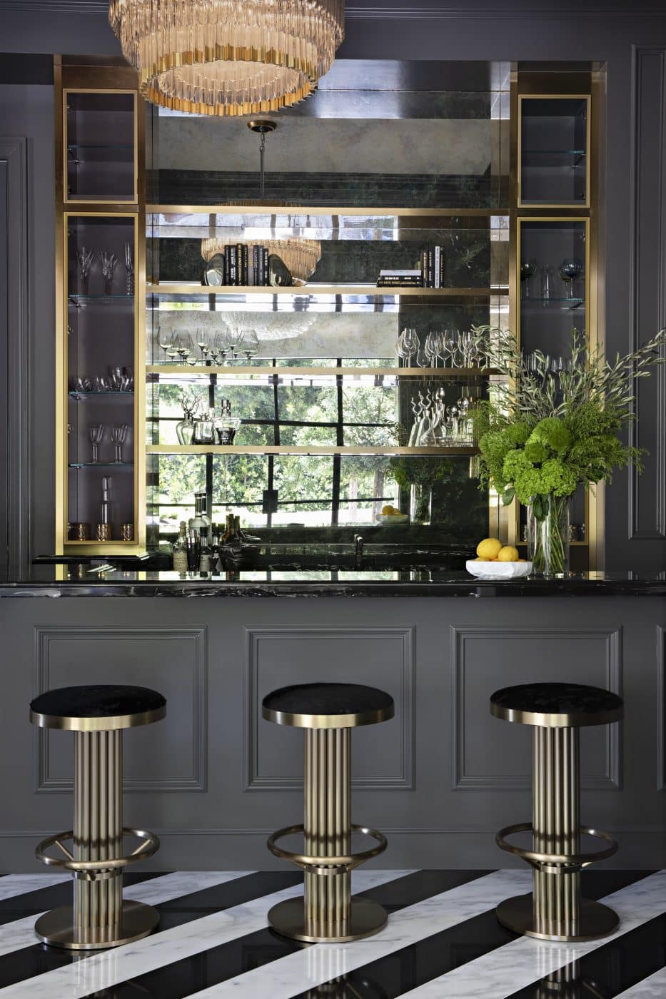 Painted a rich charcoal, the bar and game room features sleek stools and black-and-white marble floors laid in a diagonal pattern.