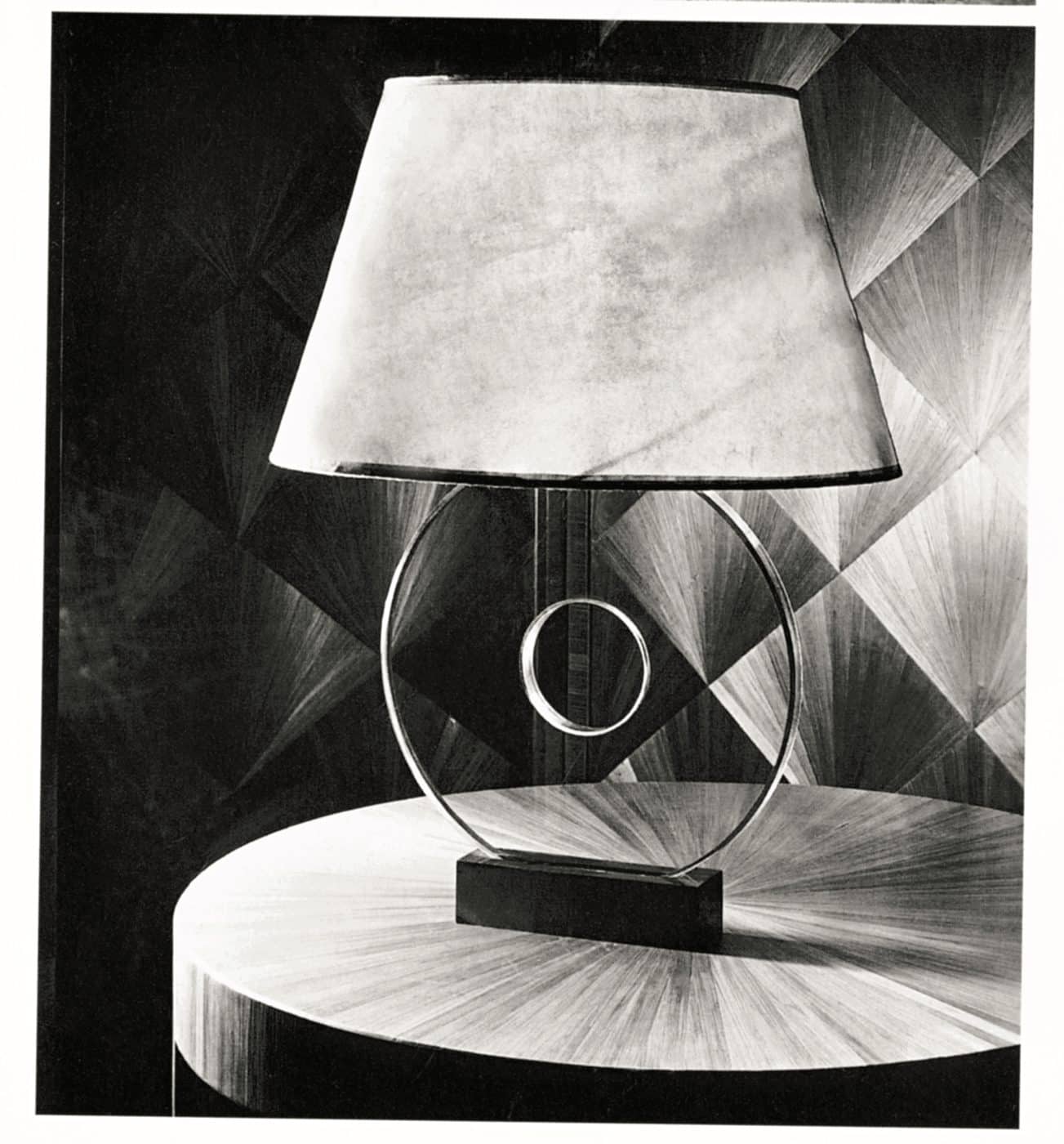 Black and white image of a Disque table lamp mounted on a disk of glass with a bronze base and parchment shade, designed by JEAN-MICHEL FRANK, c. 1922
