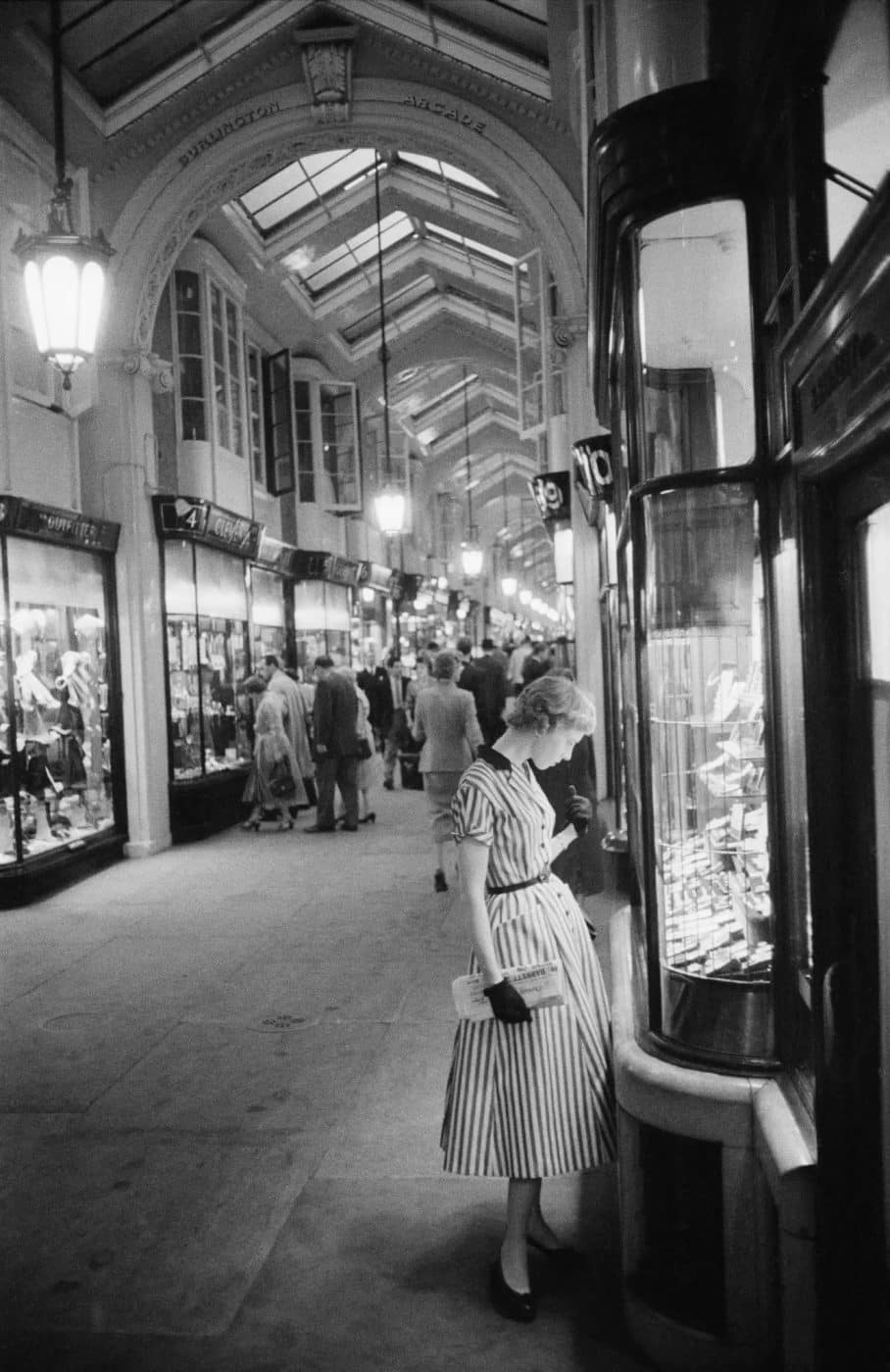 A woman browses a Burlington Arcade jewelry display in a 1955 SLIM AARONS PHOTO