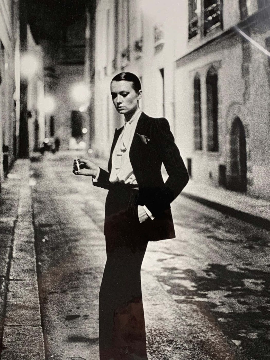 A model wears YVES SAINT LAURENT’s Le Smoking suit in HELMUT NEWTON’s 1975 photo RUE AUBRIOT. 
