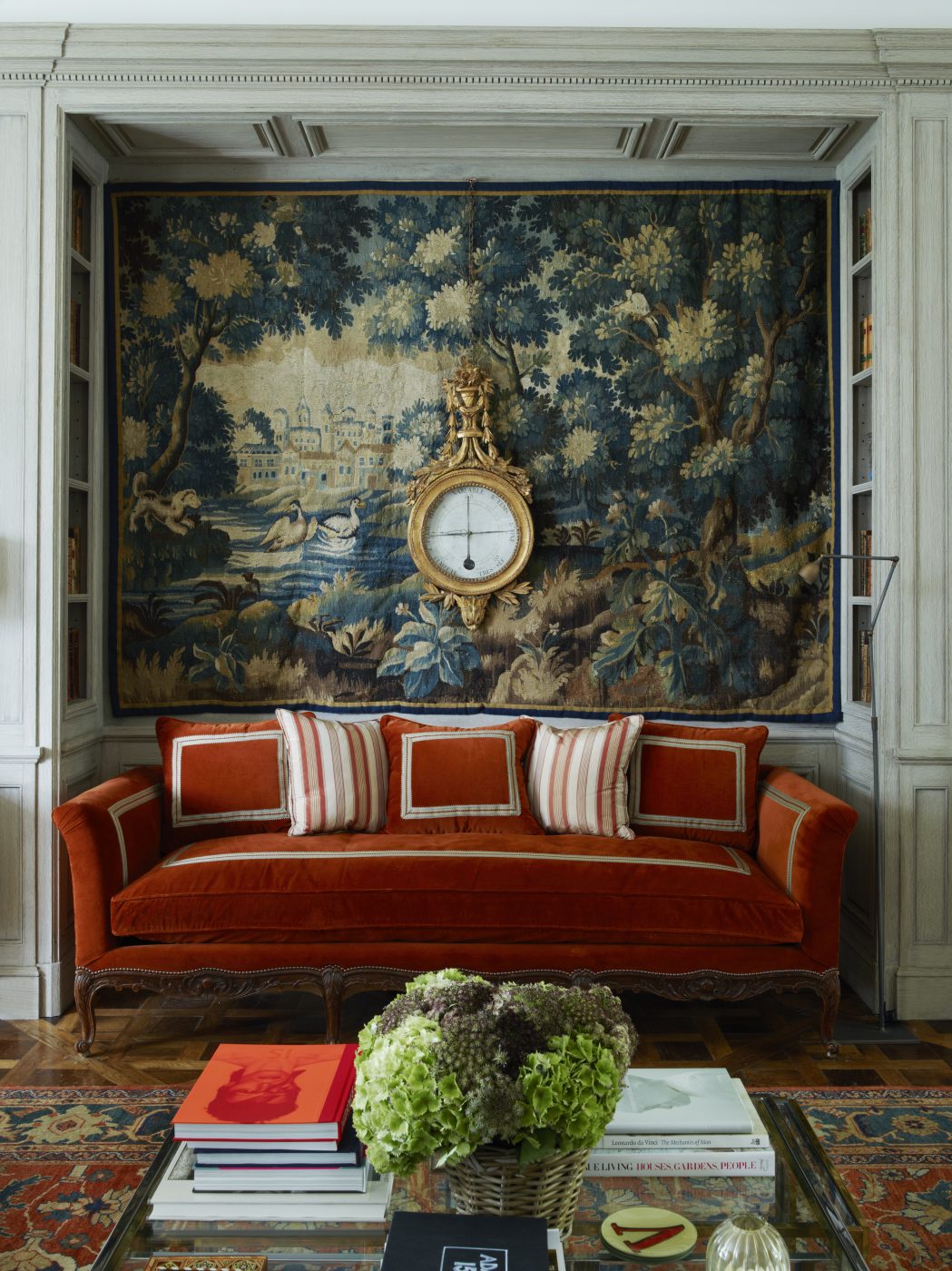 a 17th-century Flemish tapestry and an 18th-century French barometer hang above a 19th-century sofa that has been reupholstered in a mohair velvet