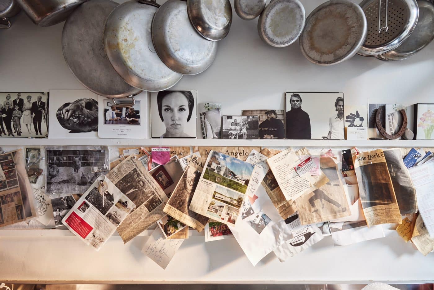 A close up of the hanging pots and pans, newspaper clippings, and black and white photography