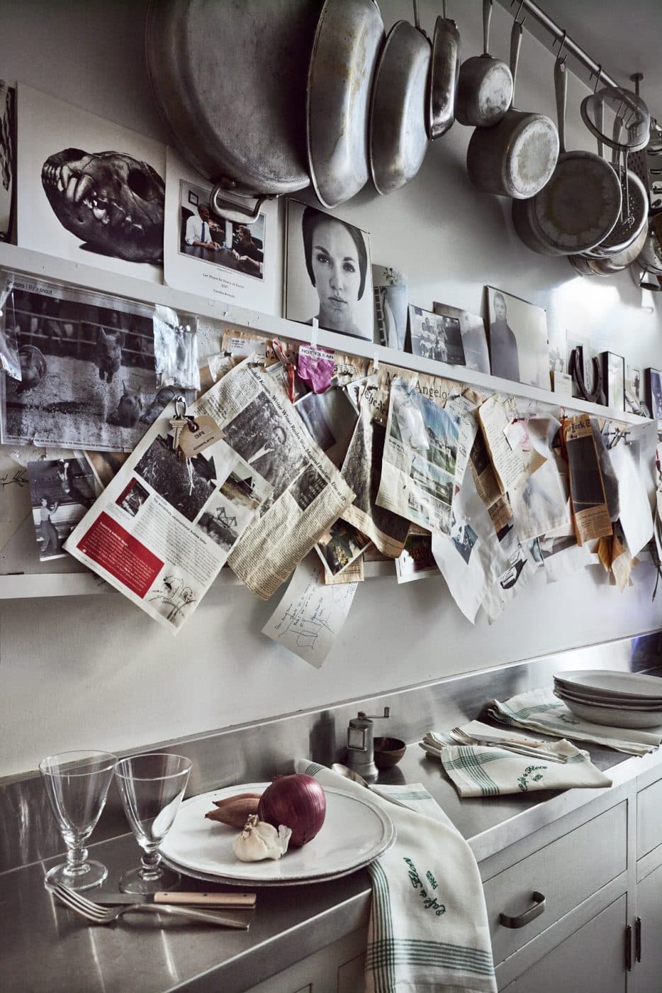 Kitchen area featuring hanging newspaper clips, black and white photography, and pots and pans