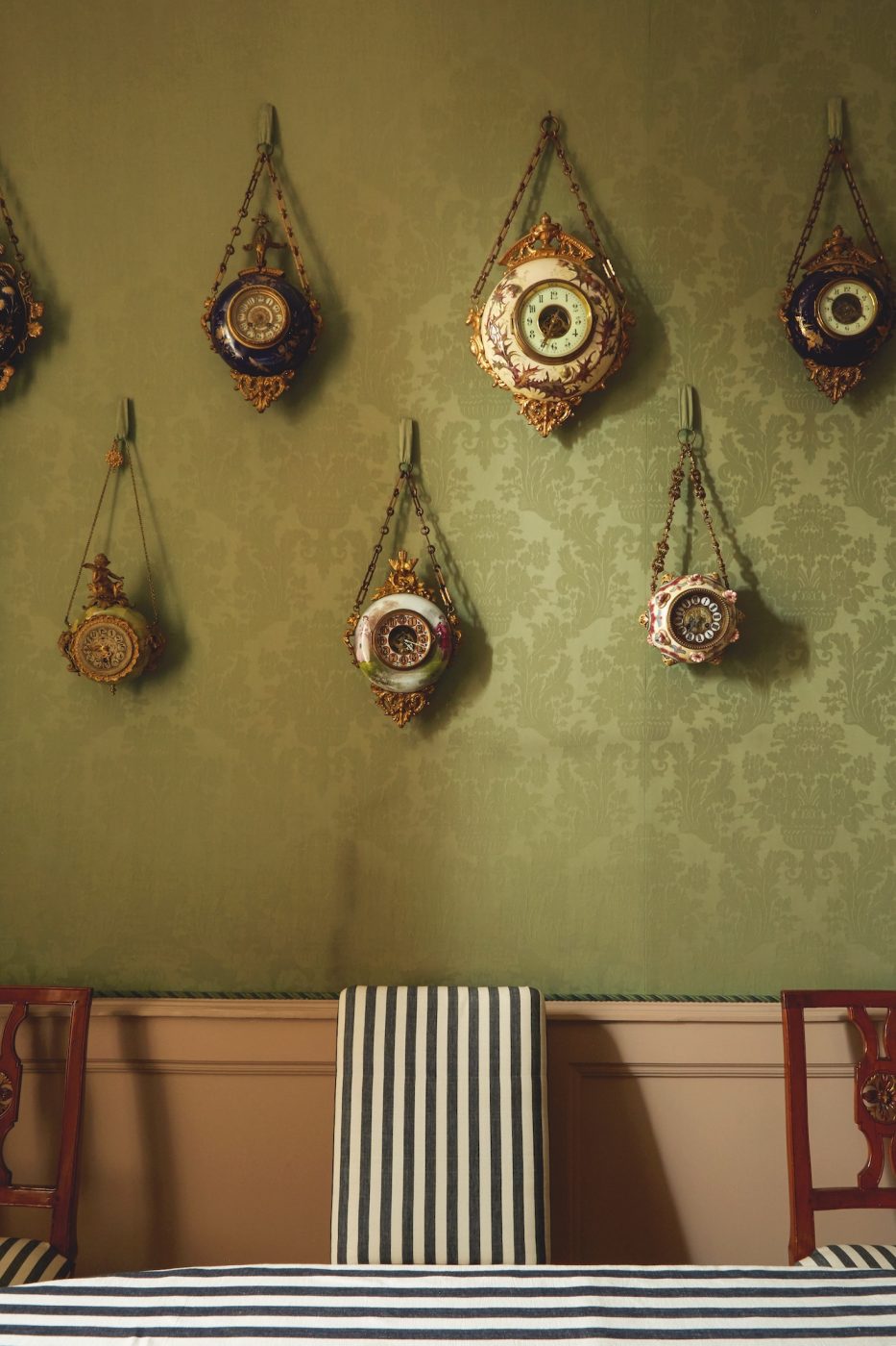 A photo of ornate clocks on top of green wallpaper