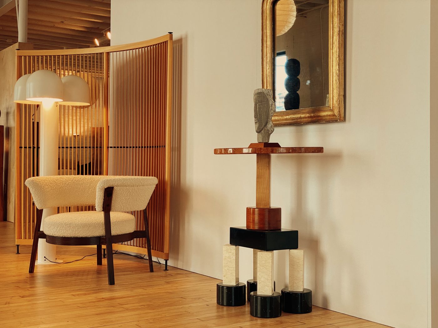 a 1980s Ettore Sottsass totem-shaped table with a carved stone head by Joan Shapiro, a Robert Sonneman floor lamp and a Eugenio Gerli lounge chair.