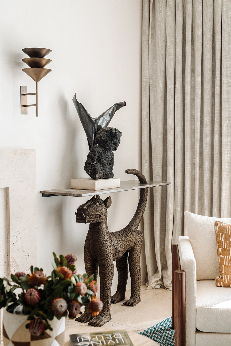 A Volker Haug brass wall sconce and a stone-top console table with a bronze leopard base