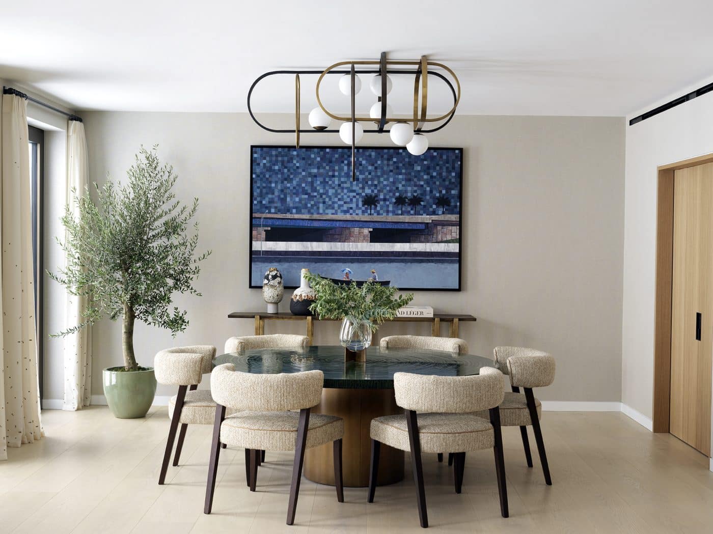 London dining room features a brass-and-bronze chandelier as well as a table with a textured top and lacquer and brass base, both designed by Miyar.