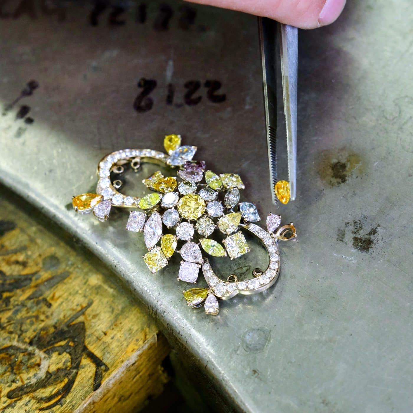  Left: GIA-certified 7.08-carat fancy orange-brown heart-shaped diamond cocktail ring, 2010 Right: A craftsperson sets a gem in this colorful brooch.