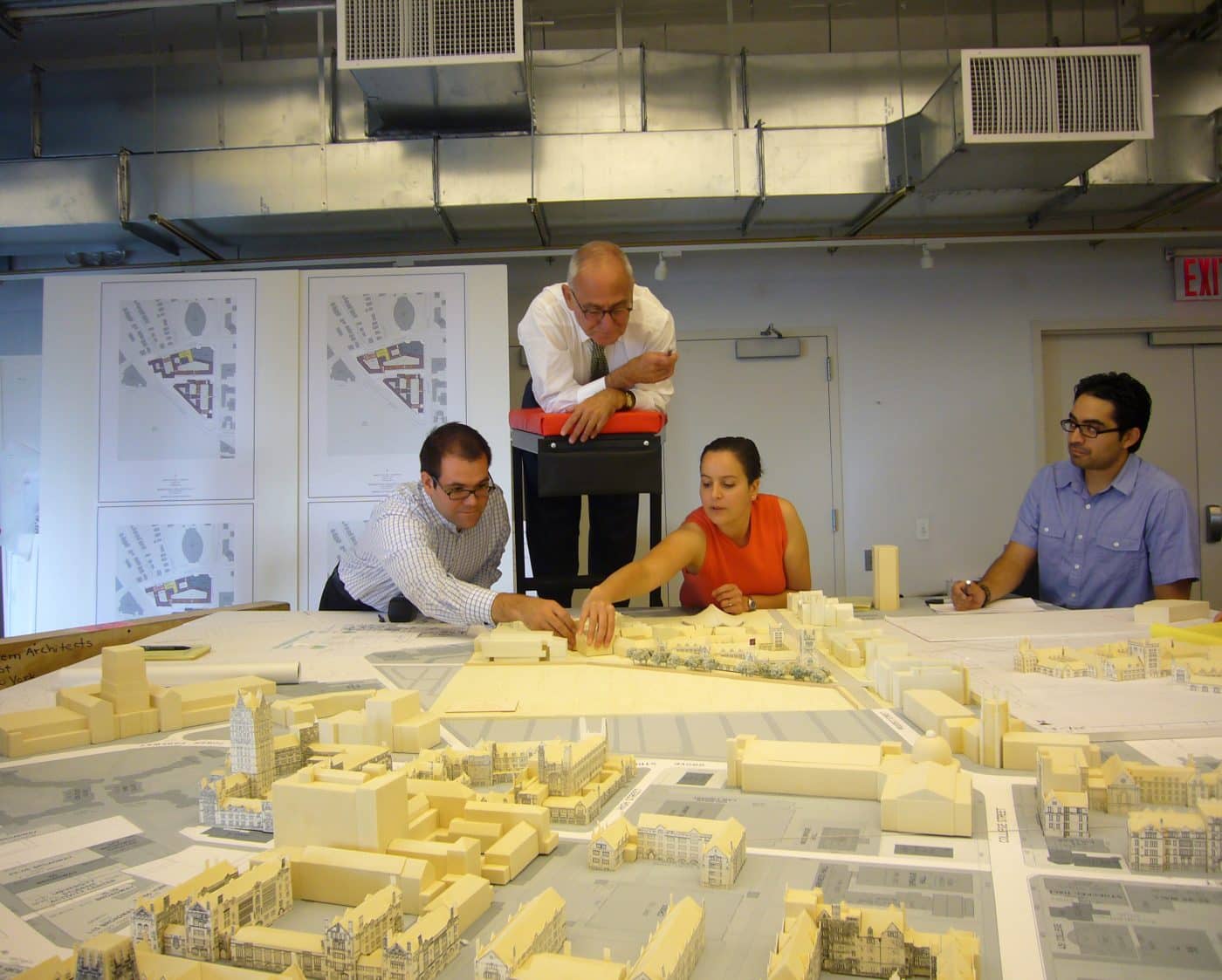 Photo of Stern looking over a model of the Yale campus with his colleagues