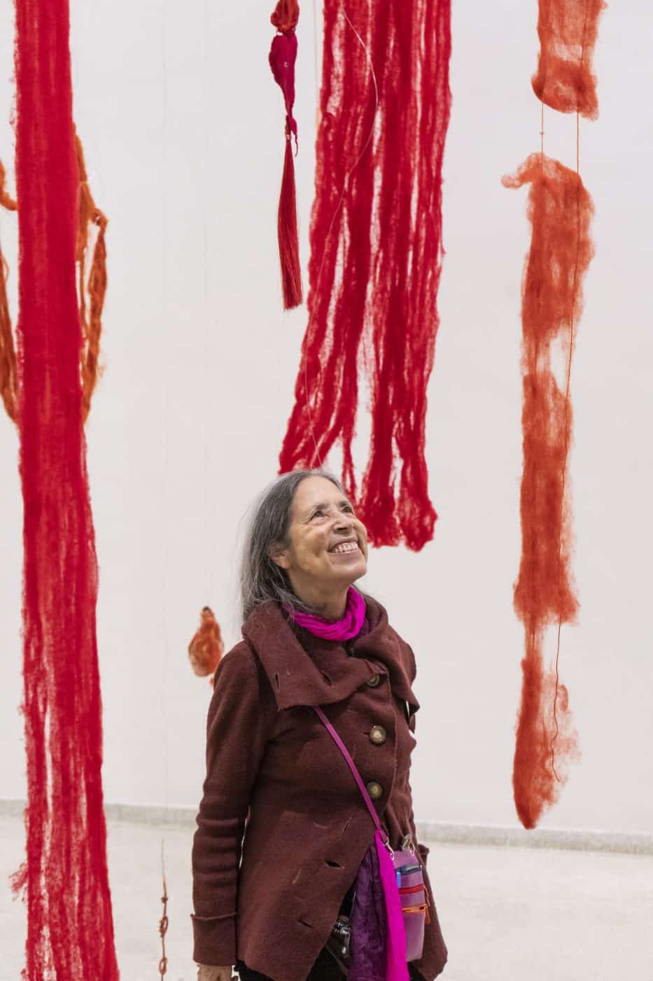 Cecilia Vicuña stands amid her new fiber-based installation Quipu del Exterminio (Extermination Quipu) suspended from the ceiling of New York's Guggenheim Museum as part of the show “Cecilia Vicuña: Spin Spin Triangulene.”