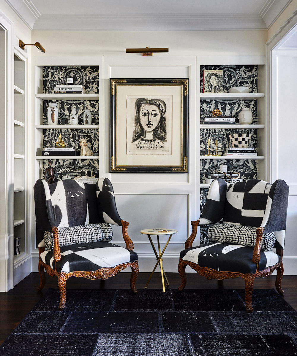 A home library designed by Jeff Schlarb with a black-and-white portrait of a woman by Picasso flanked by a pair of bergère chairs upholstered in black-and-white fabric