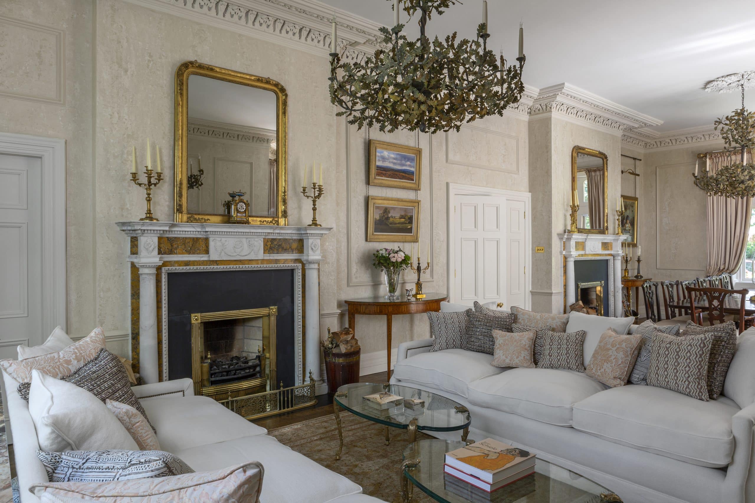 Living and dining great room of Victorian house in Dublin designed by Bryan O'Sullivan with marble fireplaces from Ryan & Smith, Maison Jansen glass oval coffee tables, leaf chandeliers