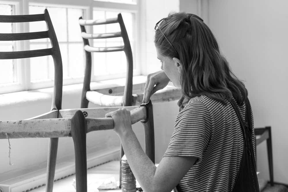 A woman works on restoring a Niels Møller Model 78 chair at Dagmar in London