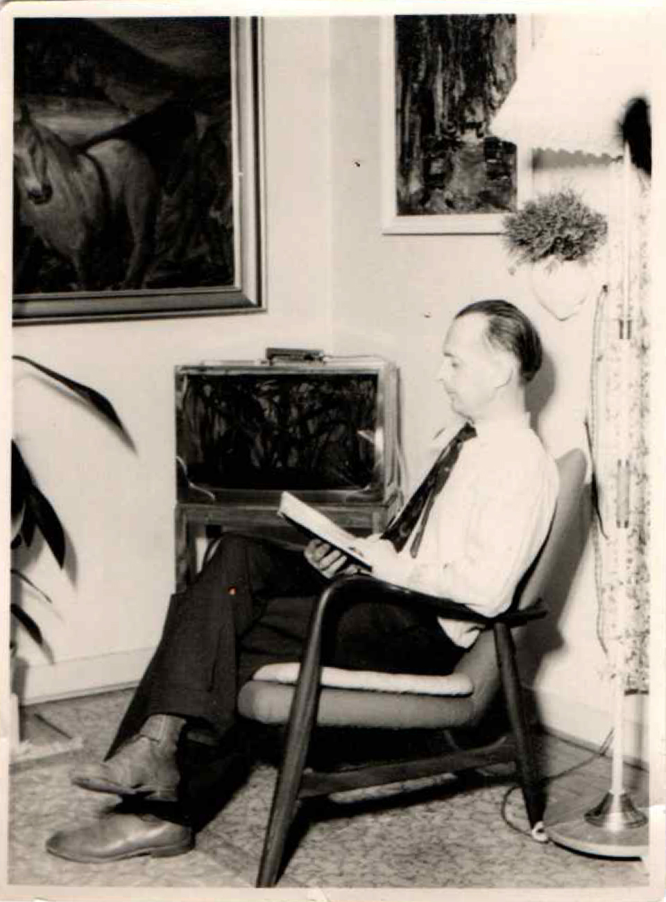 Danish upholsterer Arnold Madsen sitting in an armchair and reading at his home in Copehagen, ca. 1950