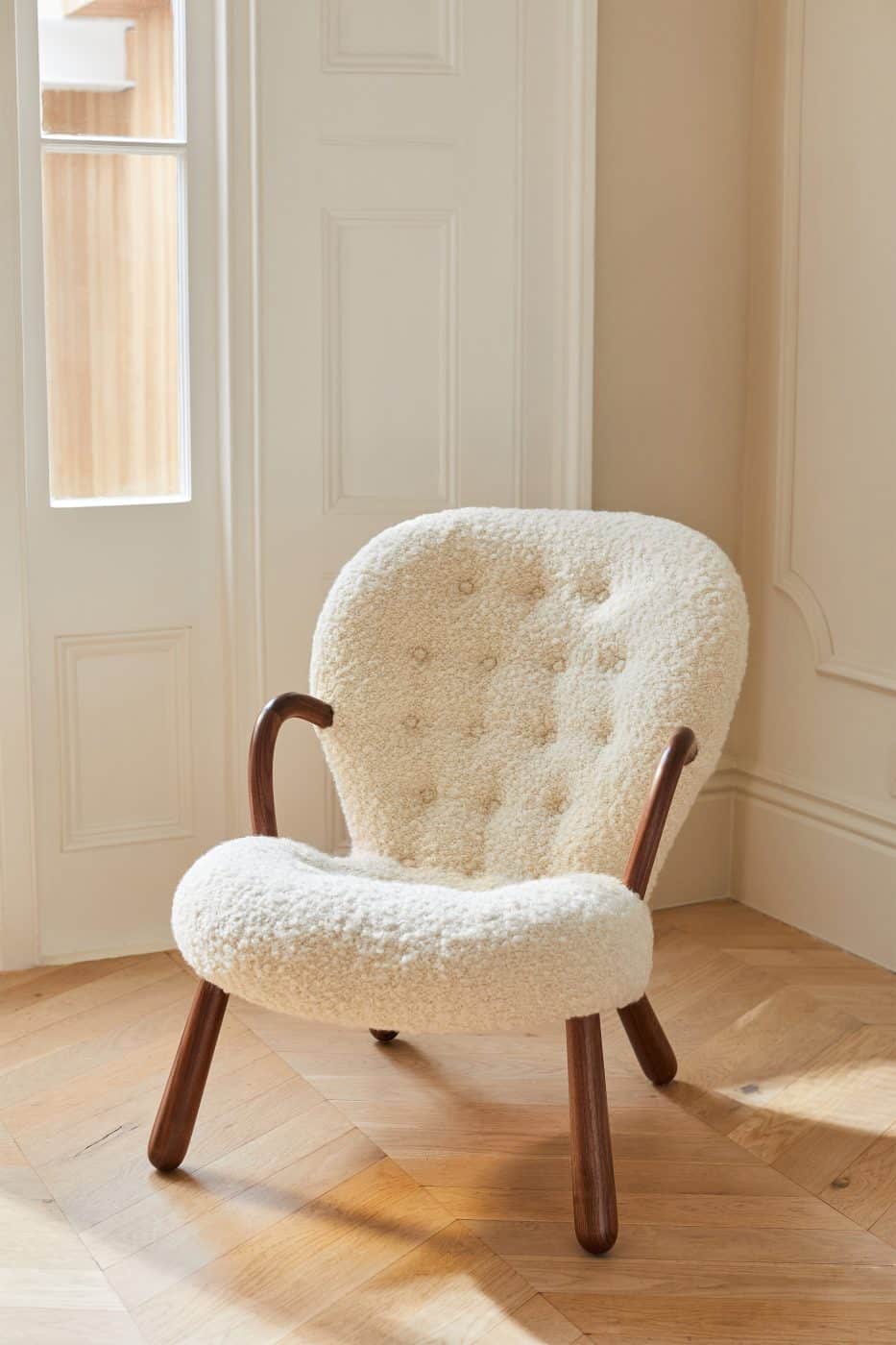 A reeditioned Clam chair with cream-colored sheepskin upholstery