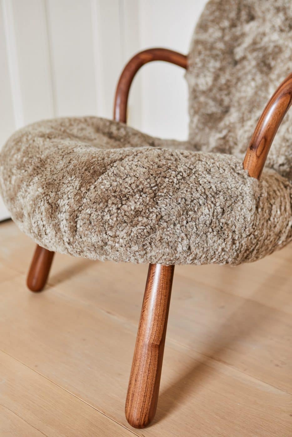 A closeup of a reeditioned Clam chair with light-brown sheepskin upholstery