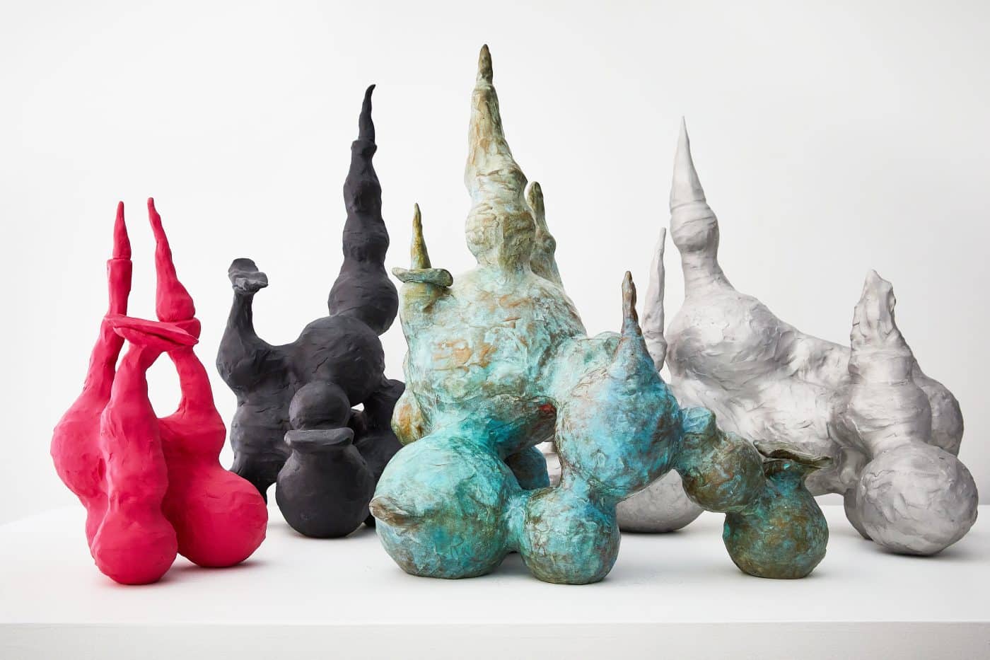 Four bulbous sculptures in fuchsia, black, turquoise and silver from Paula Hayes's "Gnomes" series