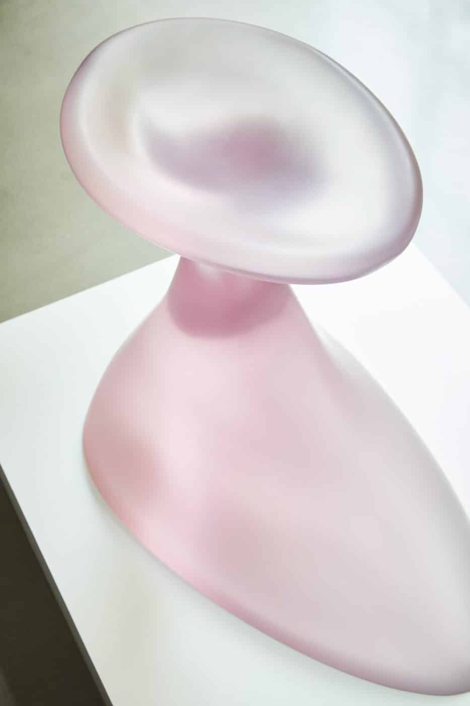A pale pink translucent silicon birdbath by Paula Hayes with a smooth amorphous form