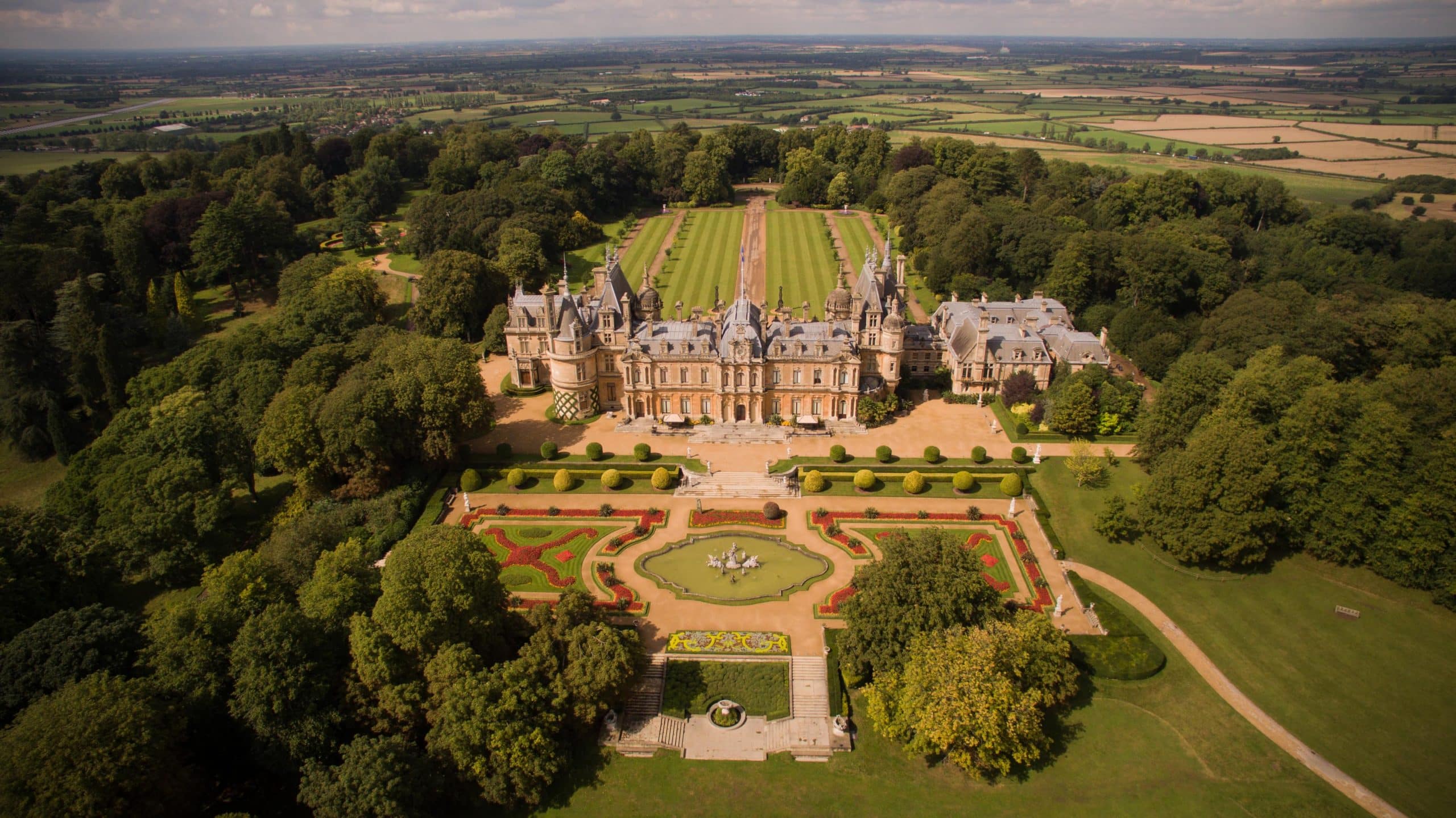 Aerial photograph of England's turreted French chateaux style Waddesdon Manor and formal gardens 