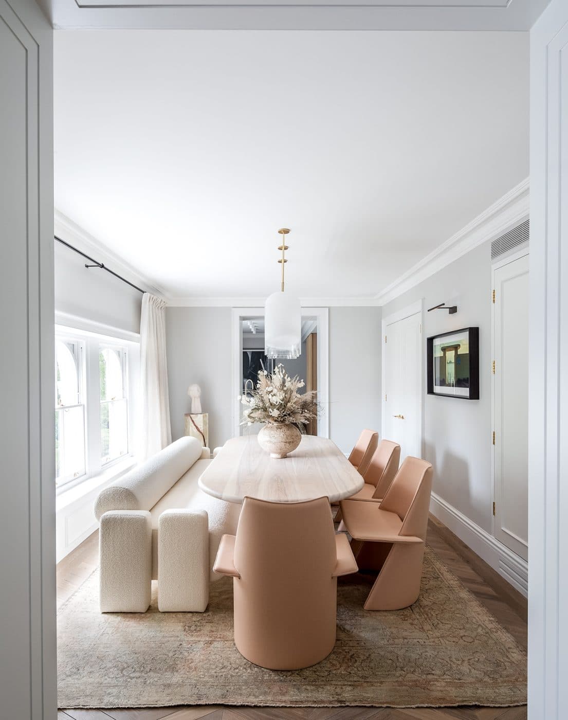 Banda interior design studio West London apartment dining room with low boucle bench and pink chairs at long oblong table