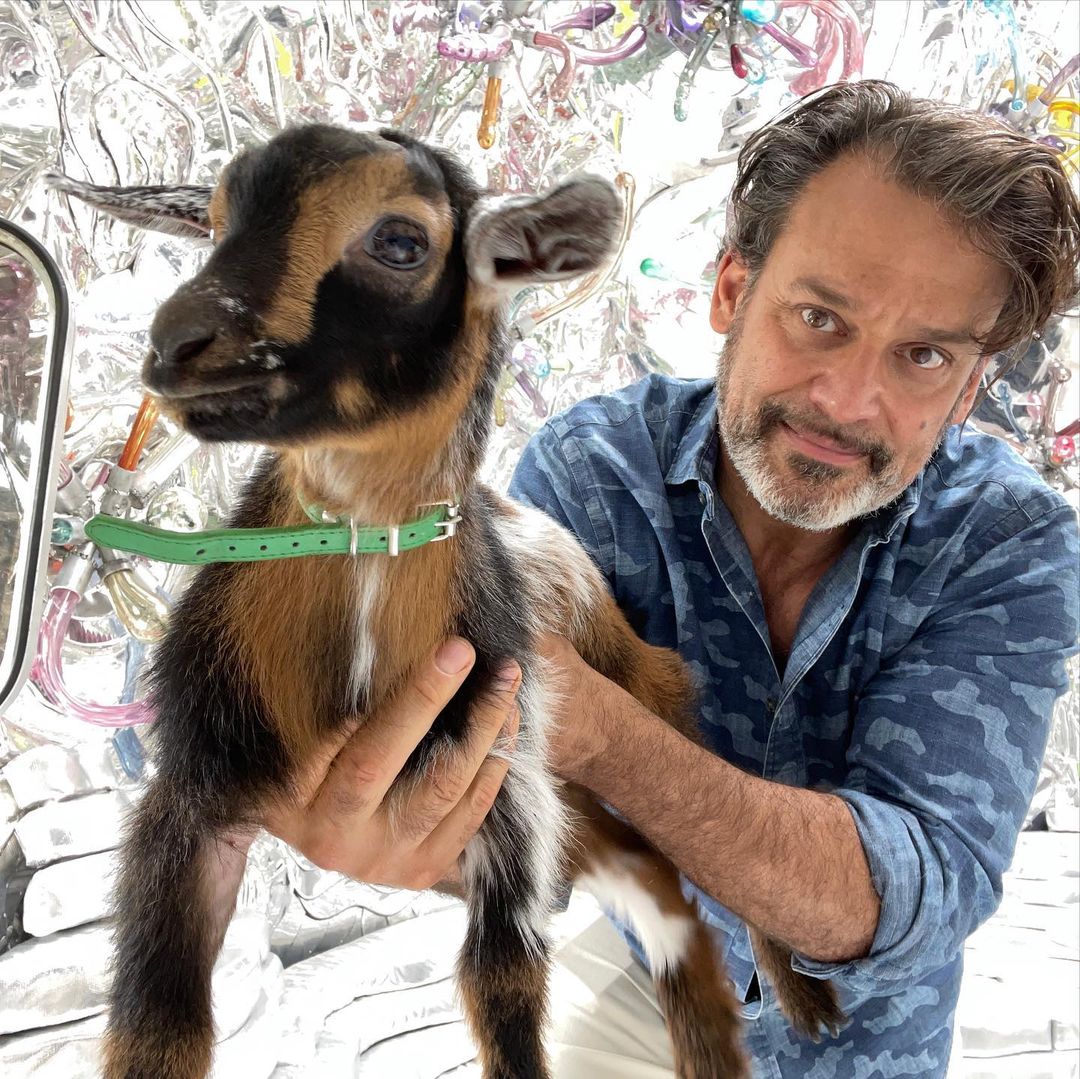 Artist Randy Polumbo poses with a goat in his site-specific installation "Bee Brook Grotto"