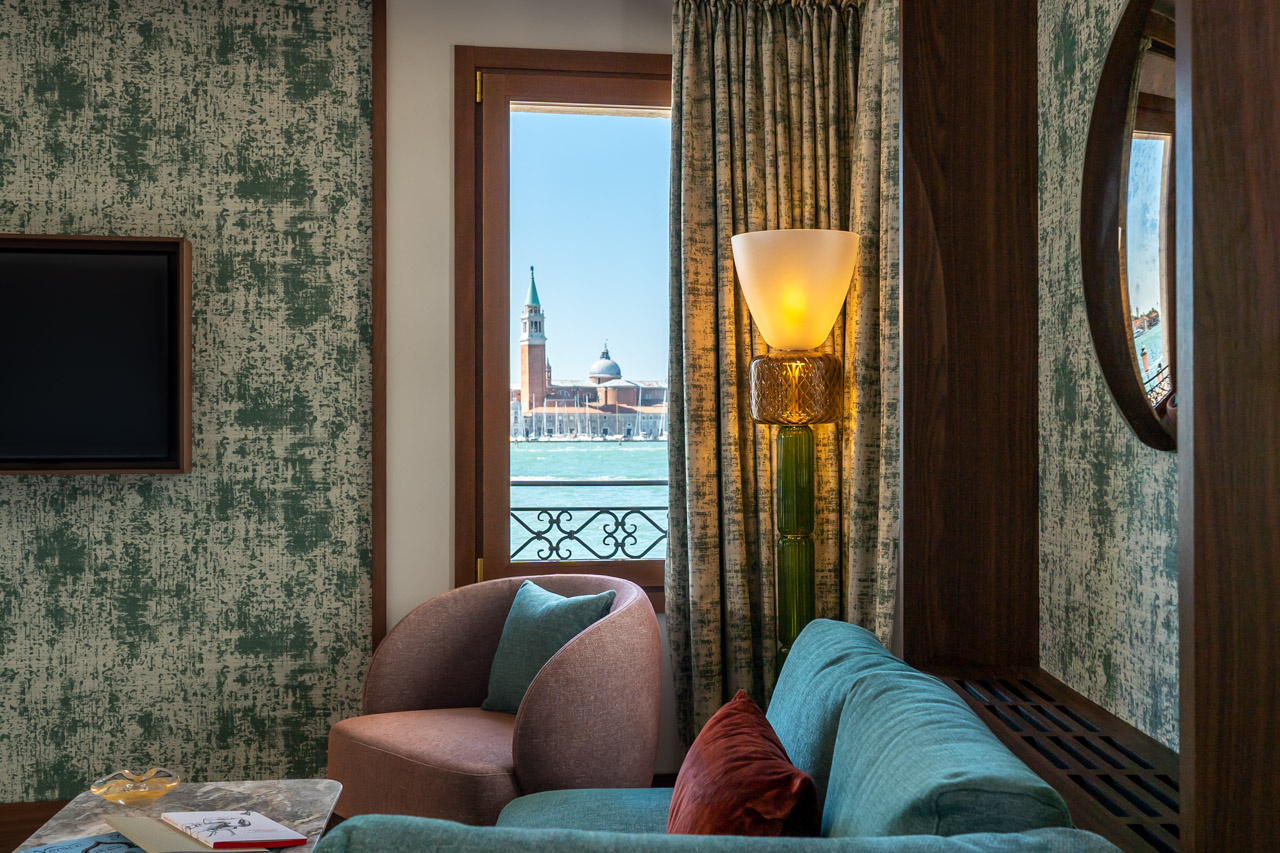 Venice's new Ca' di Dio hotel guest room with custom beds, armchairs, sofas and small tables Patricia Urquiola designed with Molteni and view through window of San Giorgio Maggiore monastery across Grand Canal