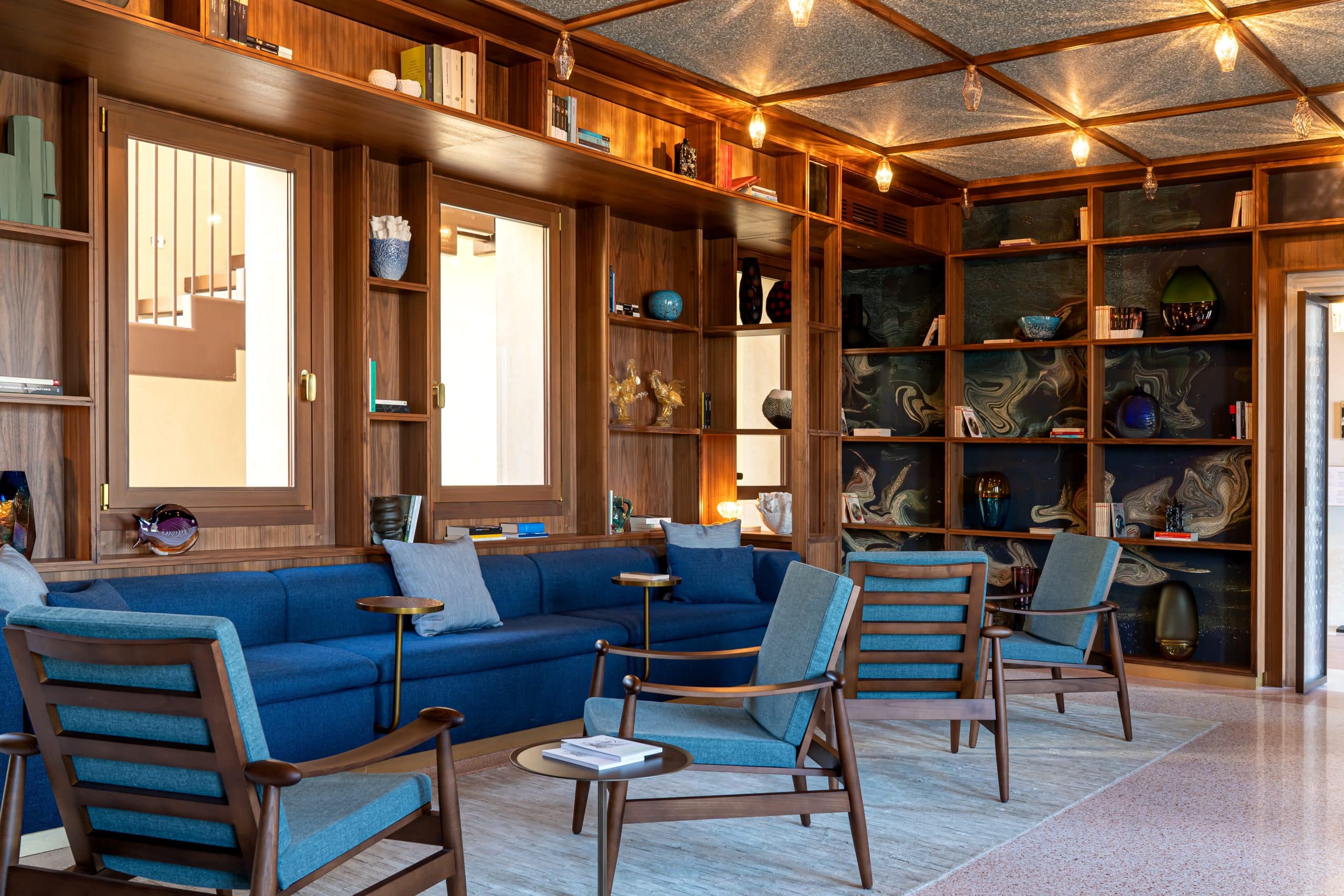 Venice's new Ca' di Dio hotel reading room in shades of blue with marbleized paper backing bookshelves. Hotel architecture and interior design by Patricia Urquiola