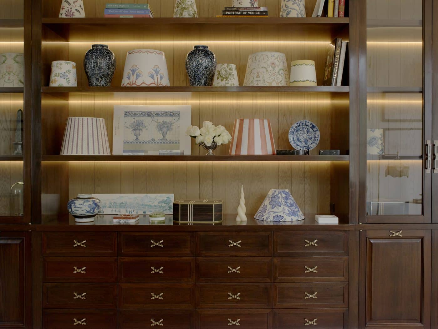 A wall unit in the Loyzaga showroom with shelves displaying books, hand-painted lampshades, marble ashtrays  and other decorative objects