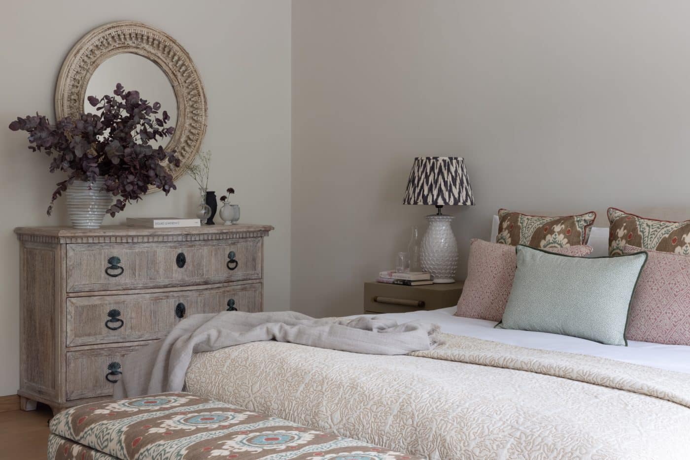 bedroom with vintage Indian mirror and pastel textiles