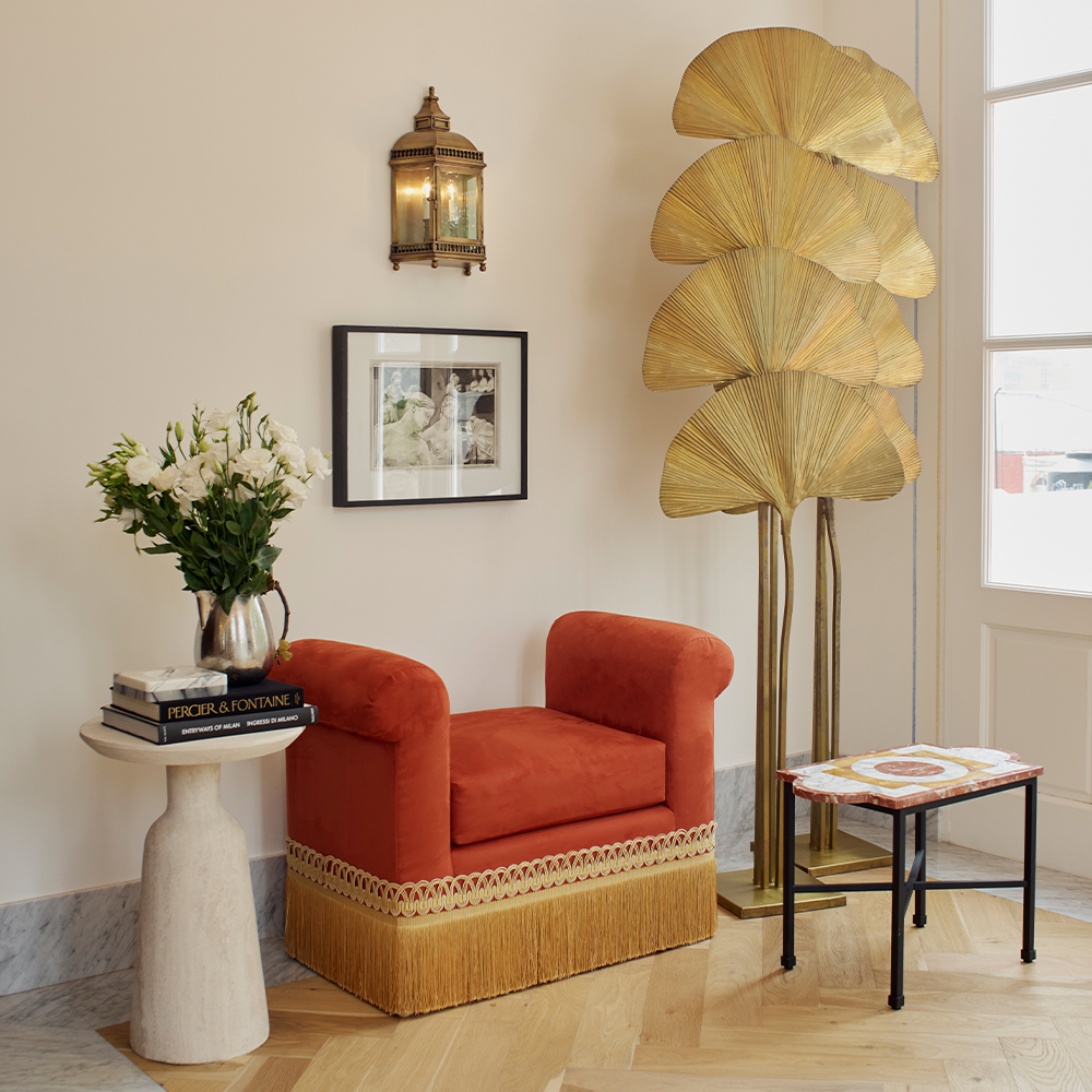 An orange seat, two side tables and a sconce by Loyzaga Studio in the firm's showroom