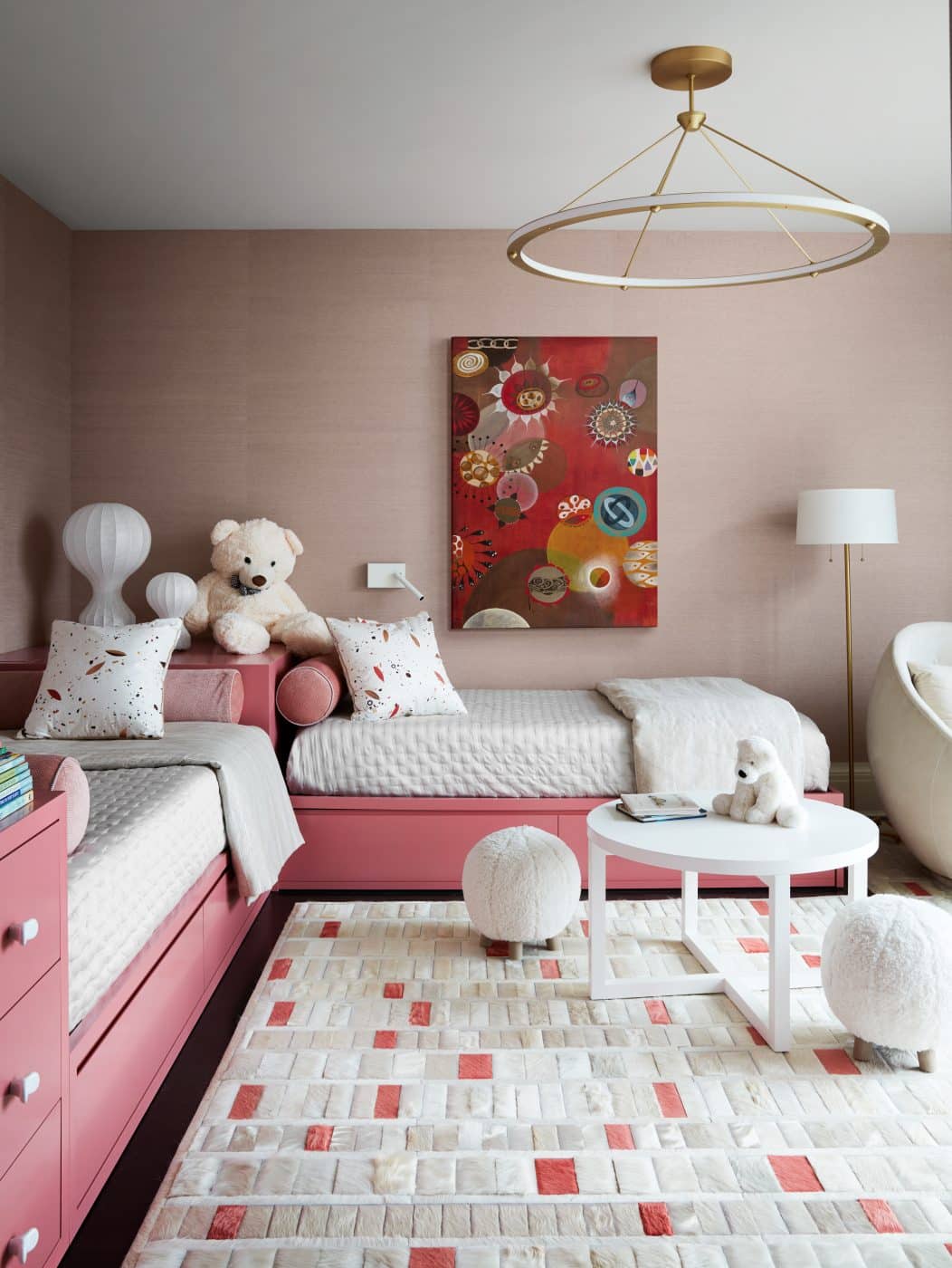 Pink child's room in Manhattan apartment designed by Drake/Anderson's Caleb Anderson Jamie Drake with pair of twin beds with shared corner headboard and colorful art