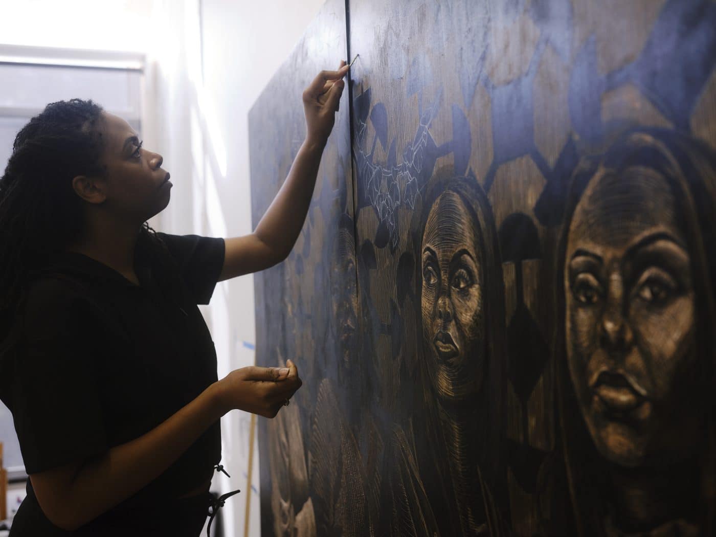 Artist LaToya M. Hobbs work on a woodcut panel in her Baltimore, MD, studio