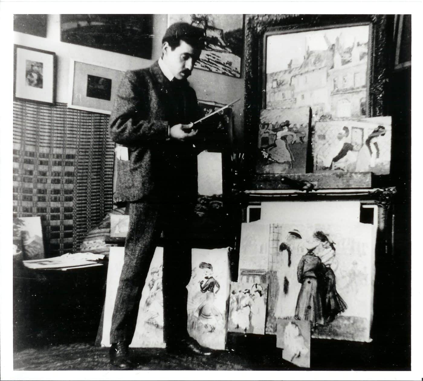 A black-and-white photo of Ludovic-Rodo Pissarro with several of his paintings in his studio