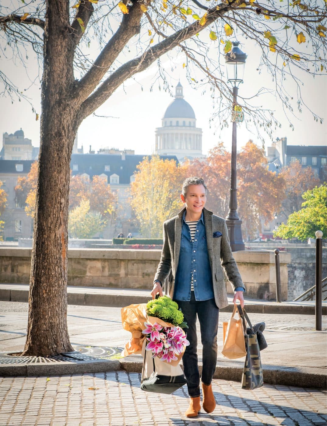 Interior designer David Jimenez portrait in Paris with tote full of market flowers from his book Parisian By Design published by Rizzoli