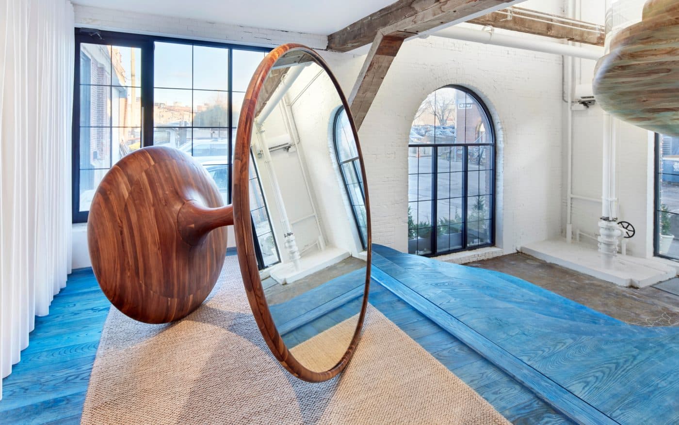 Large-scale round mirror with a rolling wooden base seen in the Ottra showroom, in the Red Hook section of Brooklyn