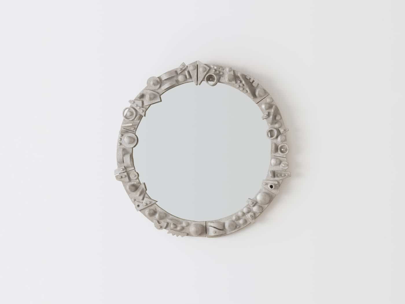 A round mirror with a sculptural gray frame by Carlos Otero