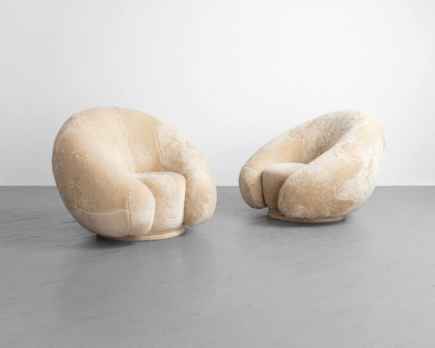 A pair of neutral-toned croissant-shaped lounge chairs by Rogan Gregory