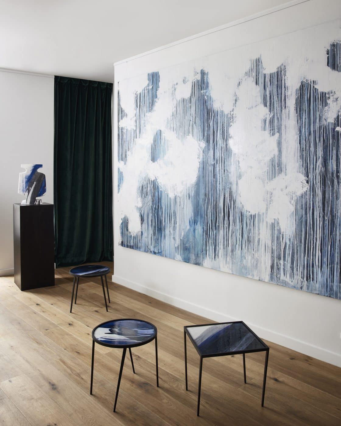 Three small, blue Benjamin Poulanges tables in front of a blue-and-white canvas by the same artist at Galerie Negropontes