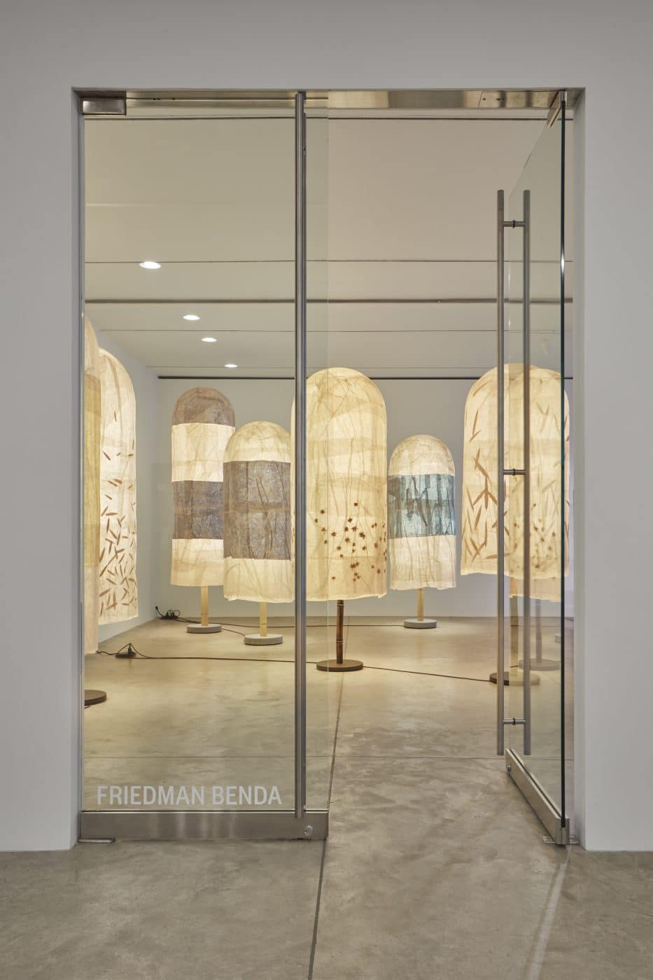 A group of Andrea Branzi floor lamps seen through a glass doorway at Friedman Benda gallery