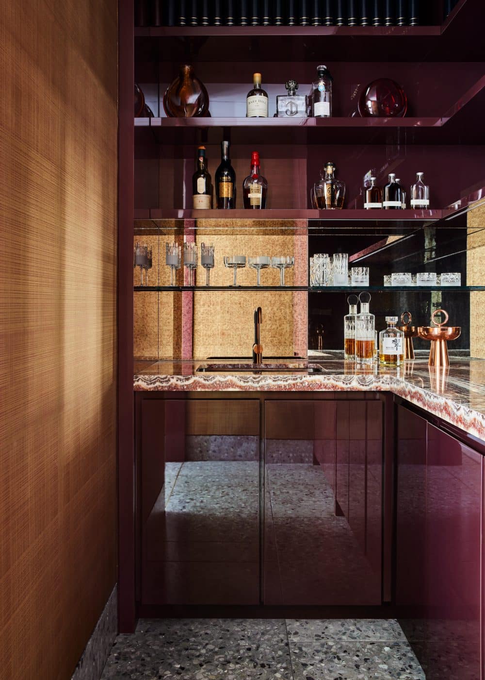 A bar with Lobmeyr glassware, lacquered cabinetry and the same terrazzo flooring found in the foyer.
