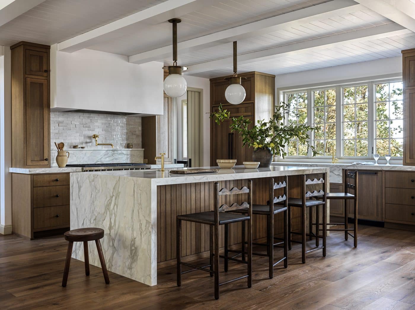 Light and Dwel's own Frankie stools line the marble-topped kitchen island, accompanied by a well-worn tripod milking stools.