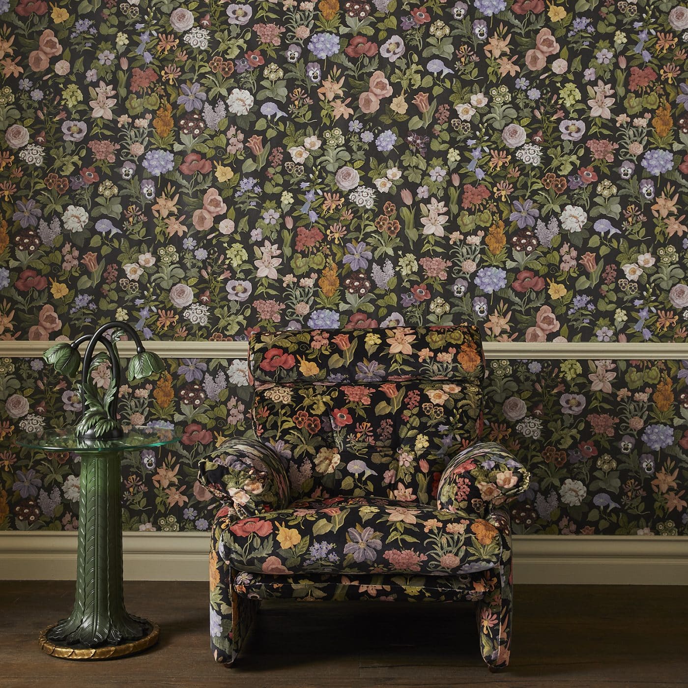 House of Hackney's Acanthus side table and table lamp next to a chair covered in the brand's Floralia print in front a wall papered with the same pattern