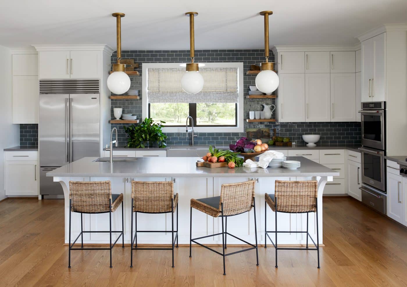 Palechek barstools pull up to an ample kitchen island with Urban Electric Pipe Hang pendant lights above. The custom-colored tiles are by Waterworks.