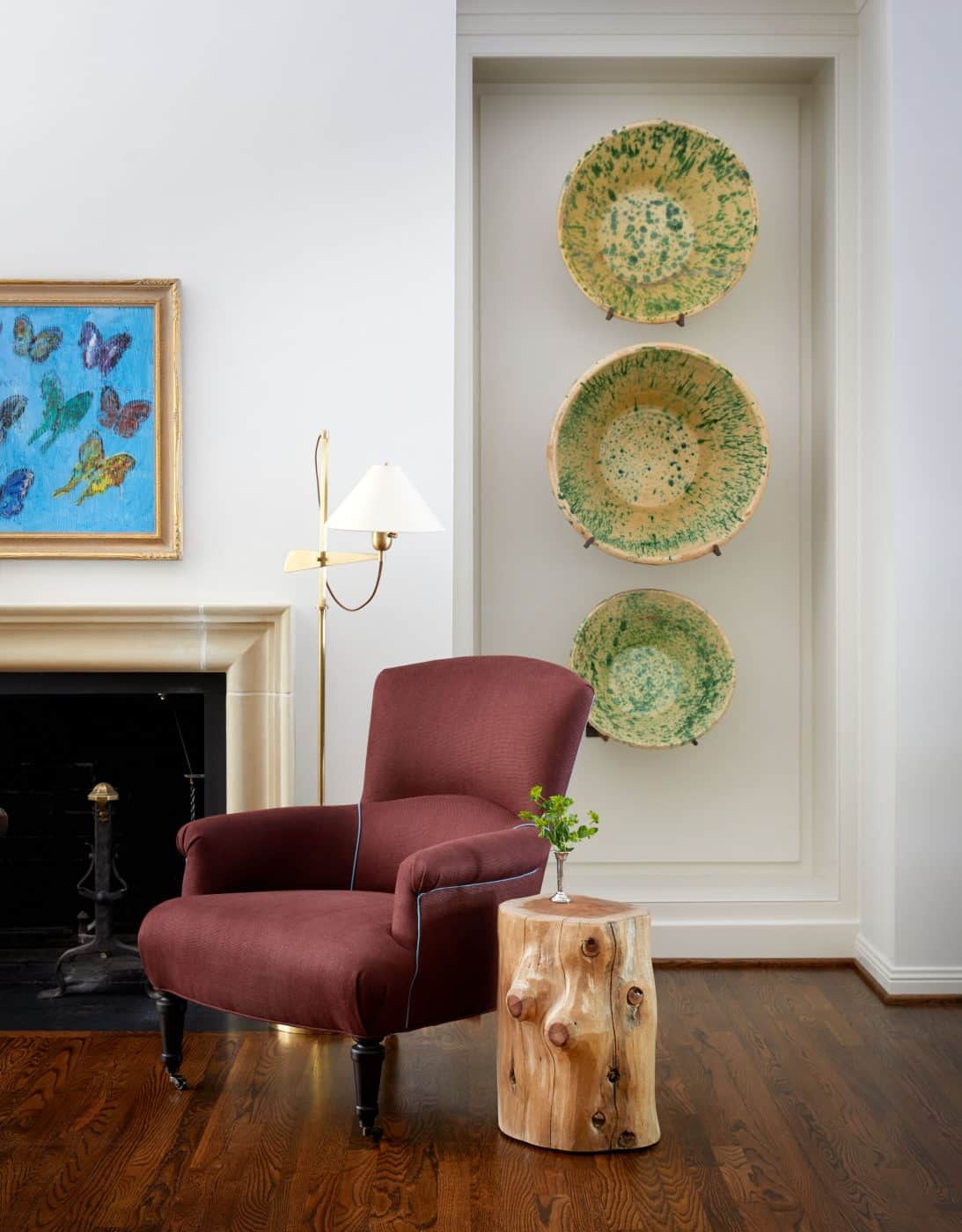 Surrounding the fireplace in the Houston home are a Hunt Slonem butterfly painting, antique Spanish ceramic bowls from Antica Collection, a Victorian wingback chair and a tree-trunk side table. 